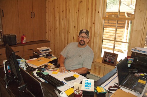 man with glasses sits behind work desk at colorado guest ranch lodge