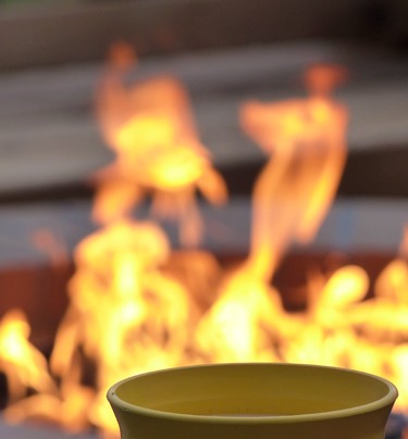 close up of top of a citronella candle with fire pit burning in background