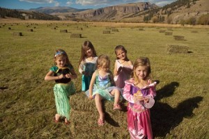 five little girls stand in foreground among hay bales and colorado san juan mountains in the background