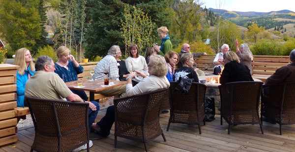 group sit on open deck with wine and blazing fire pit