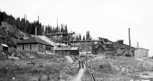 historic photo of two miners walking down hill from fluorspar mill