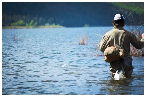 peaceful calm water of the riop grand fills the photo with the back of the fly fisherman to the camera, off to the right of the photo