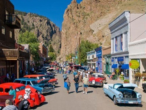 small arts town of creede with cliffs in background and car show vehicles and viewers in foreground