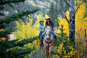 women on horseback through aspen
