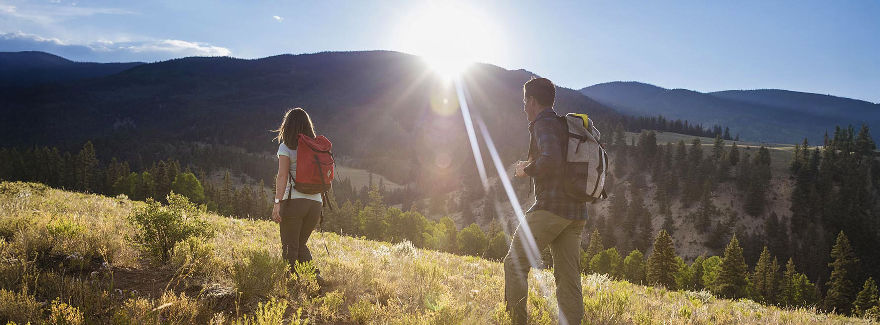 couple hiking, sun rays over hills